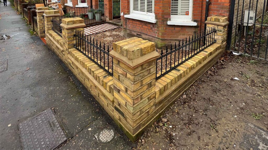 A yellow brick wall and a red and white victorian path in checkerboard style.