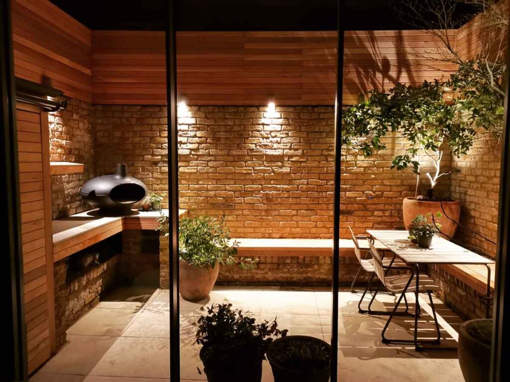A small courtyard garden in Chiswick, lit up at night time.