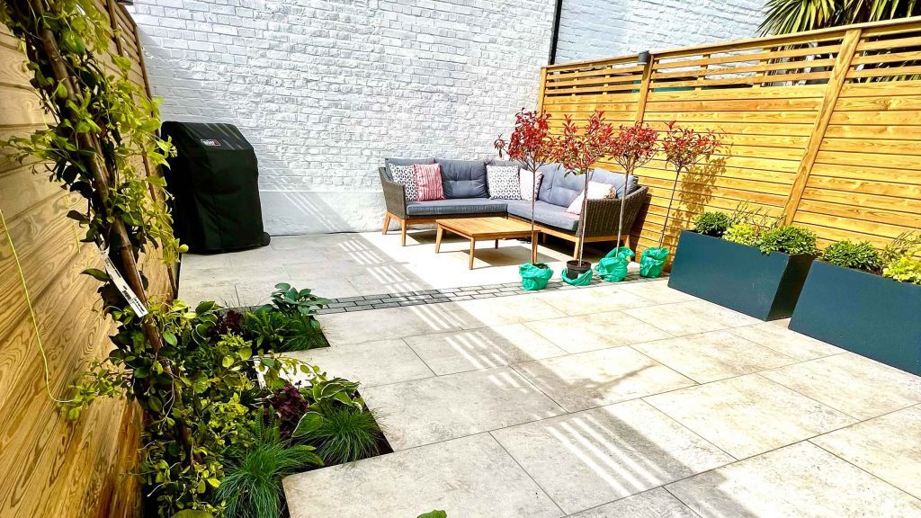 A garden completely paved in porcelain tiles and planted in cut outs of the tiles and raised planters.