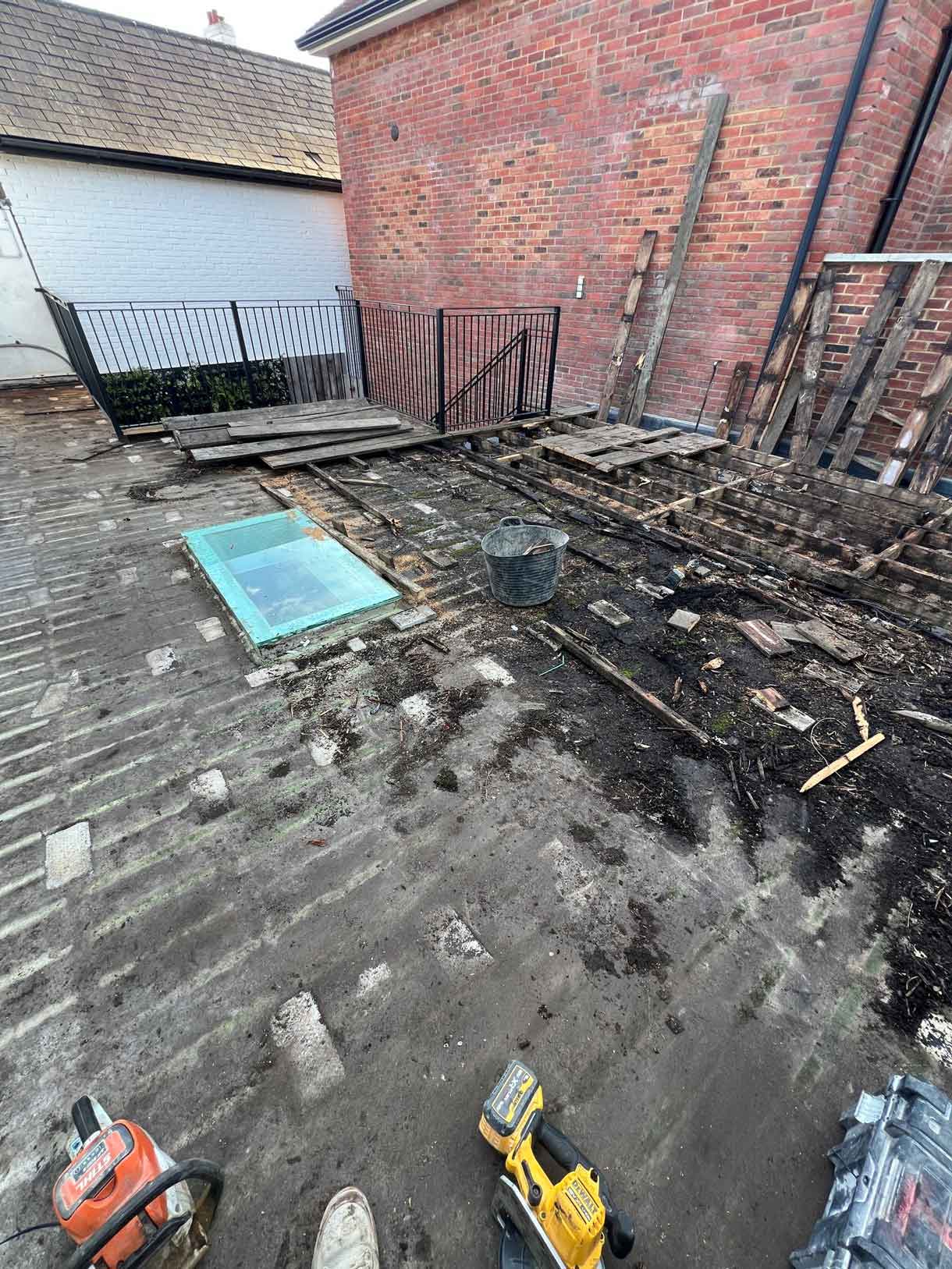 Roof terrace before renovation showing rotten wooden decking around a skylight.