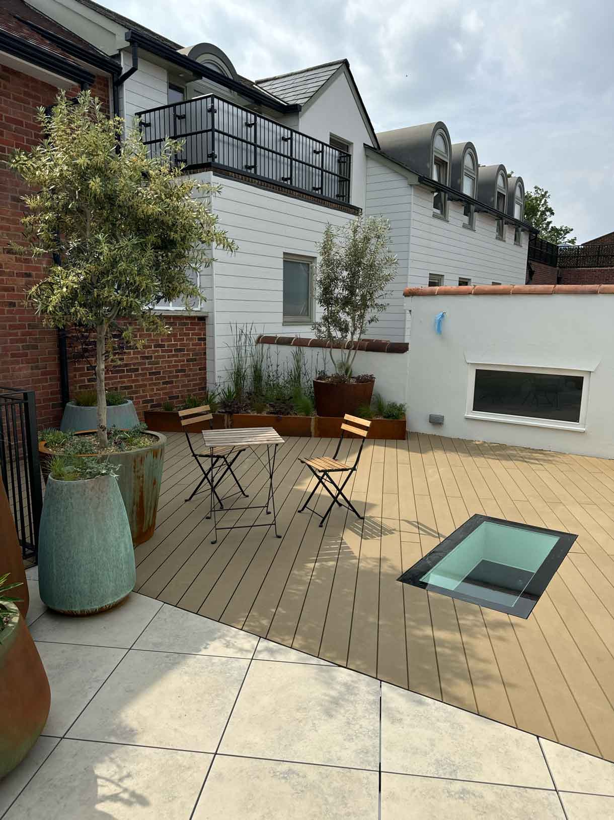 Completed roof garden with porcelain paving, planters, and outdoor seating.