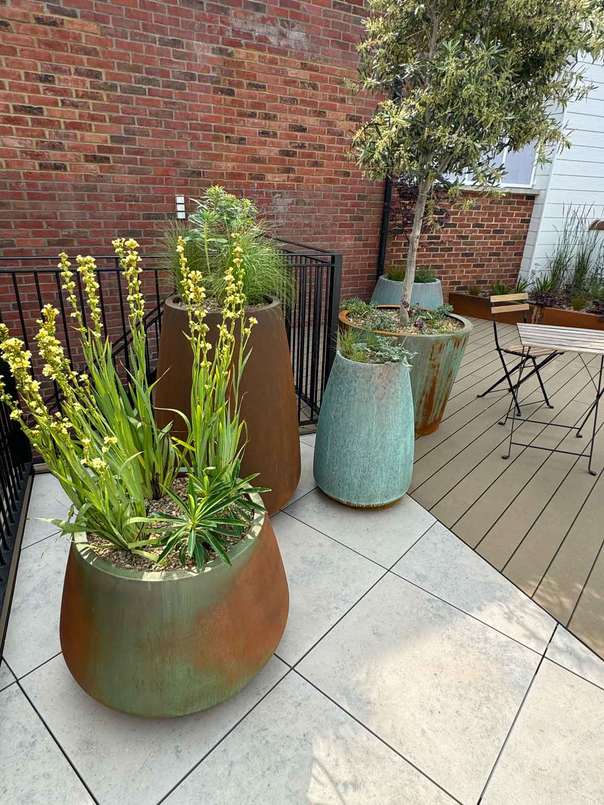 Large planters with trees and greenery on roof terrace with porcelain paving.