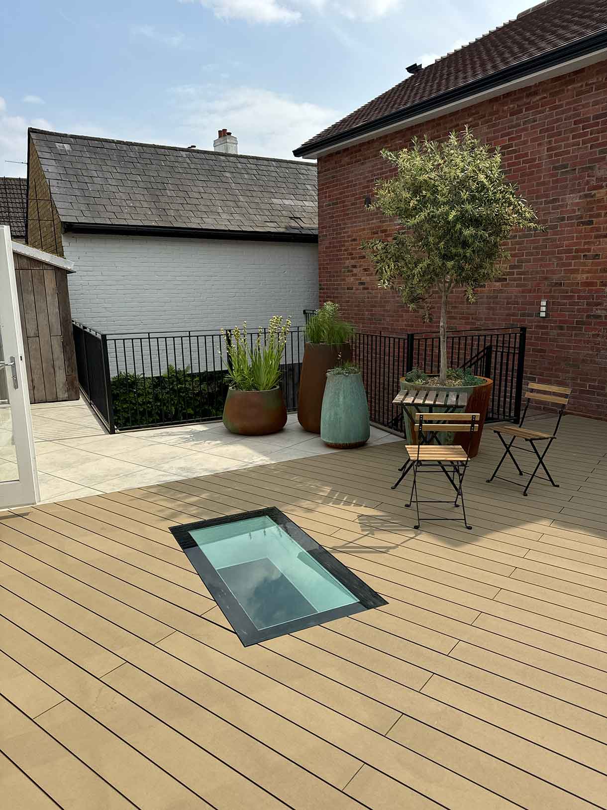 Finished roof terrace with skylight, potted trees, and outdoor chairs.