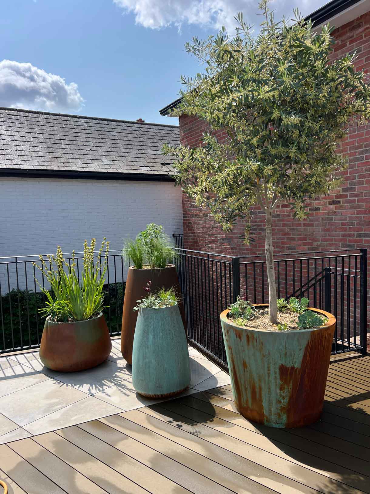Decorative planters with tall greenery on roof garden beside skylight.