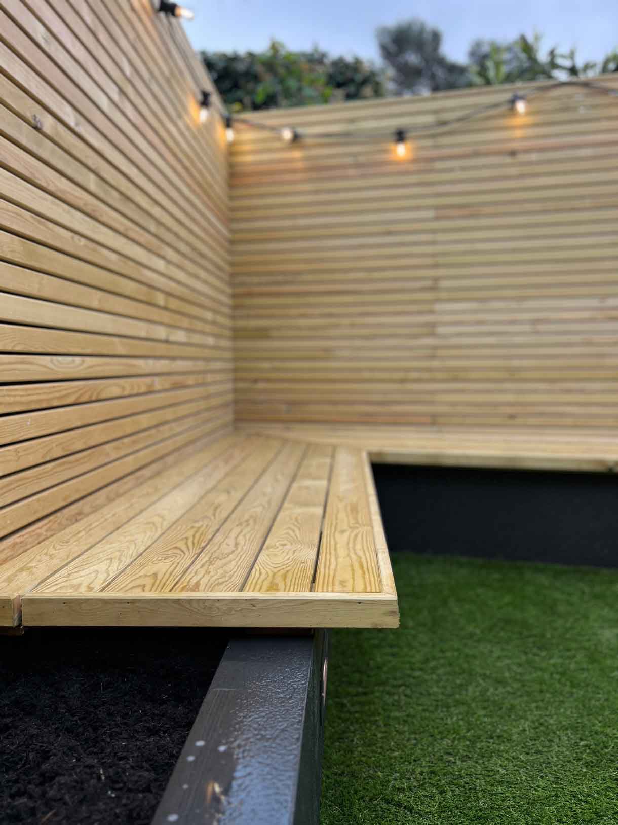 Restored courtyard garden with planting and lawn against timber-clad fencing.
