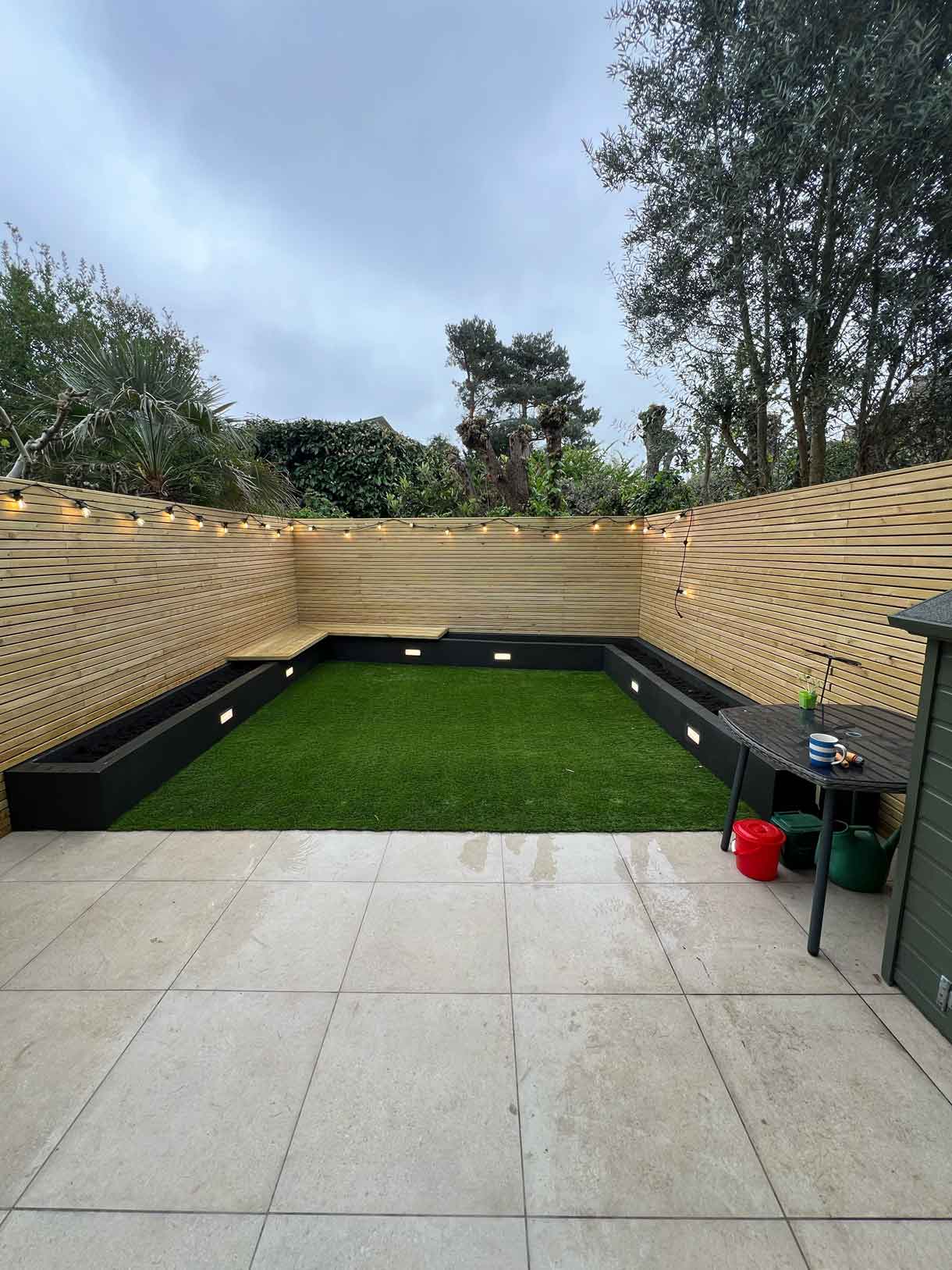 Courtyard garden with new lawn, timber cladding, and built-in seating.