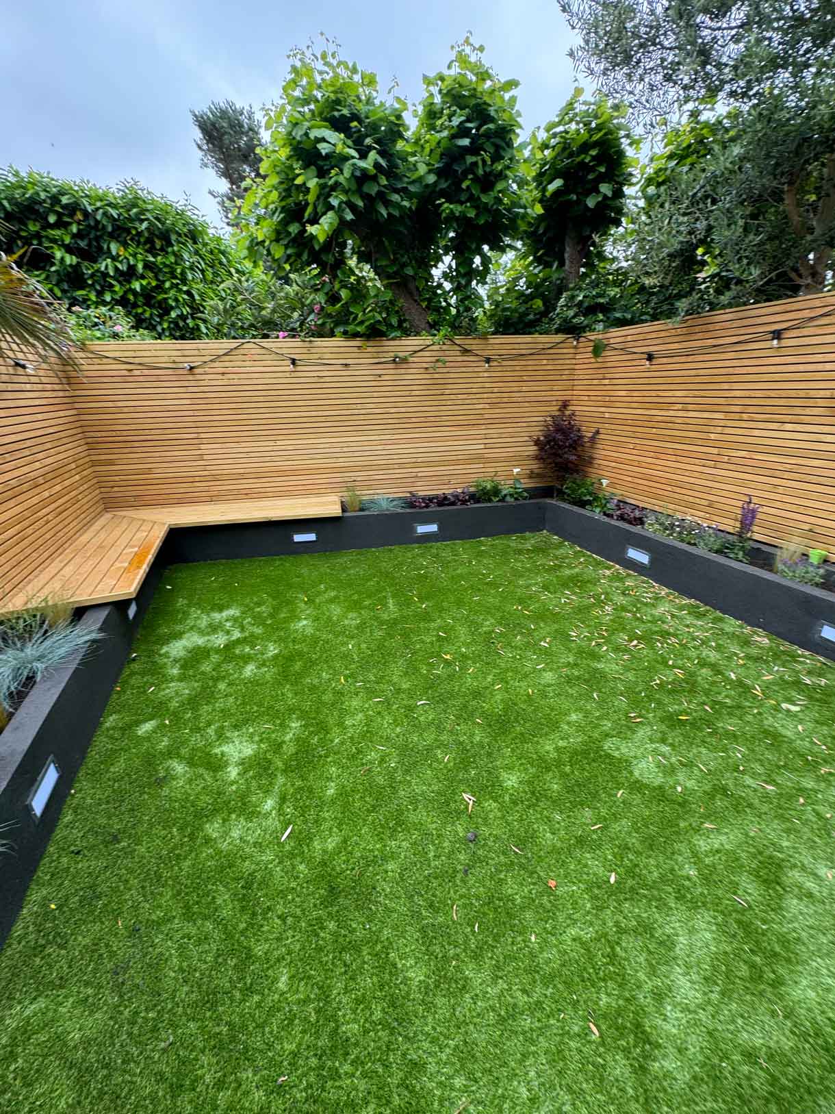 Courtyard garden with new timber battens, lawn, and built-in seating.