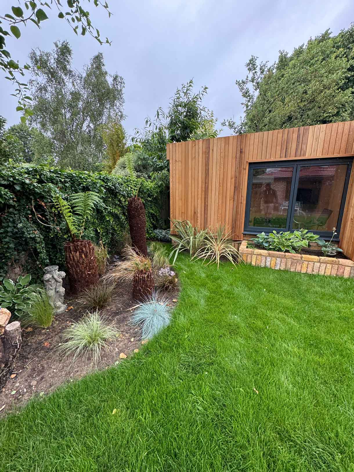 Garden room framed by greenery with new turf laid in front.