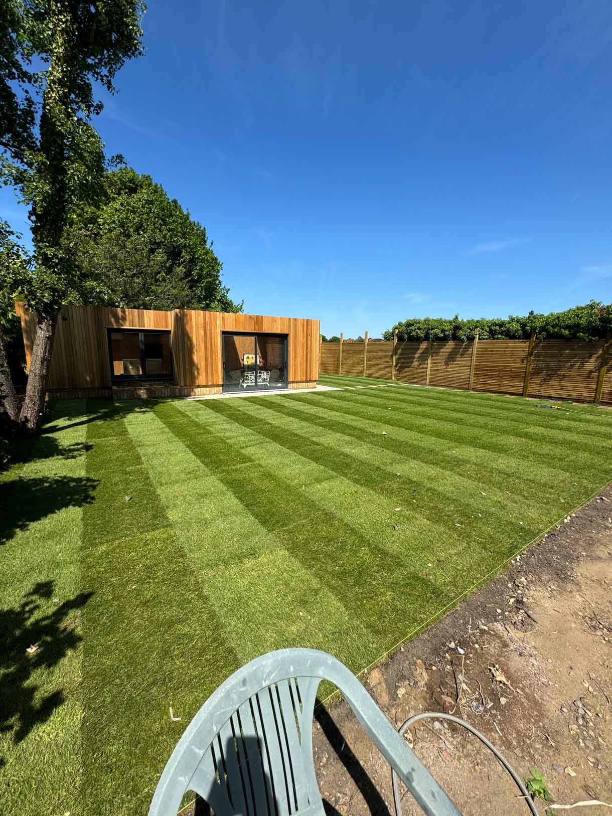 Freshly laid striped lawn leading up to a wooden garden room.