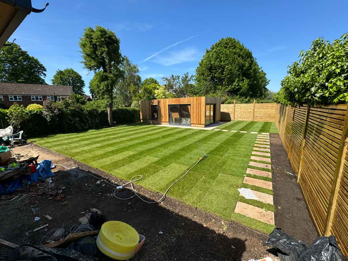 Freshly laid striped lawn with garden room in the distance.