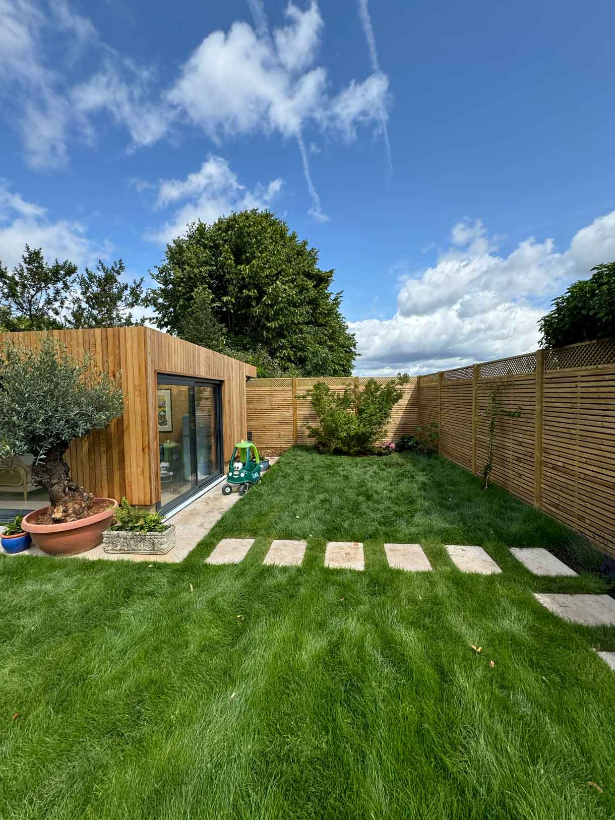 Stepping stone path along lawn leading to modern garden room.