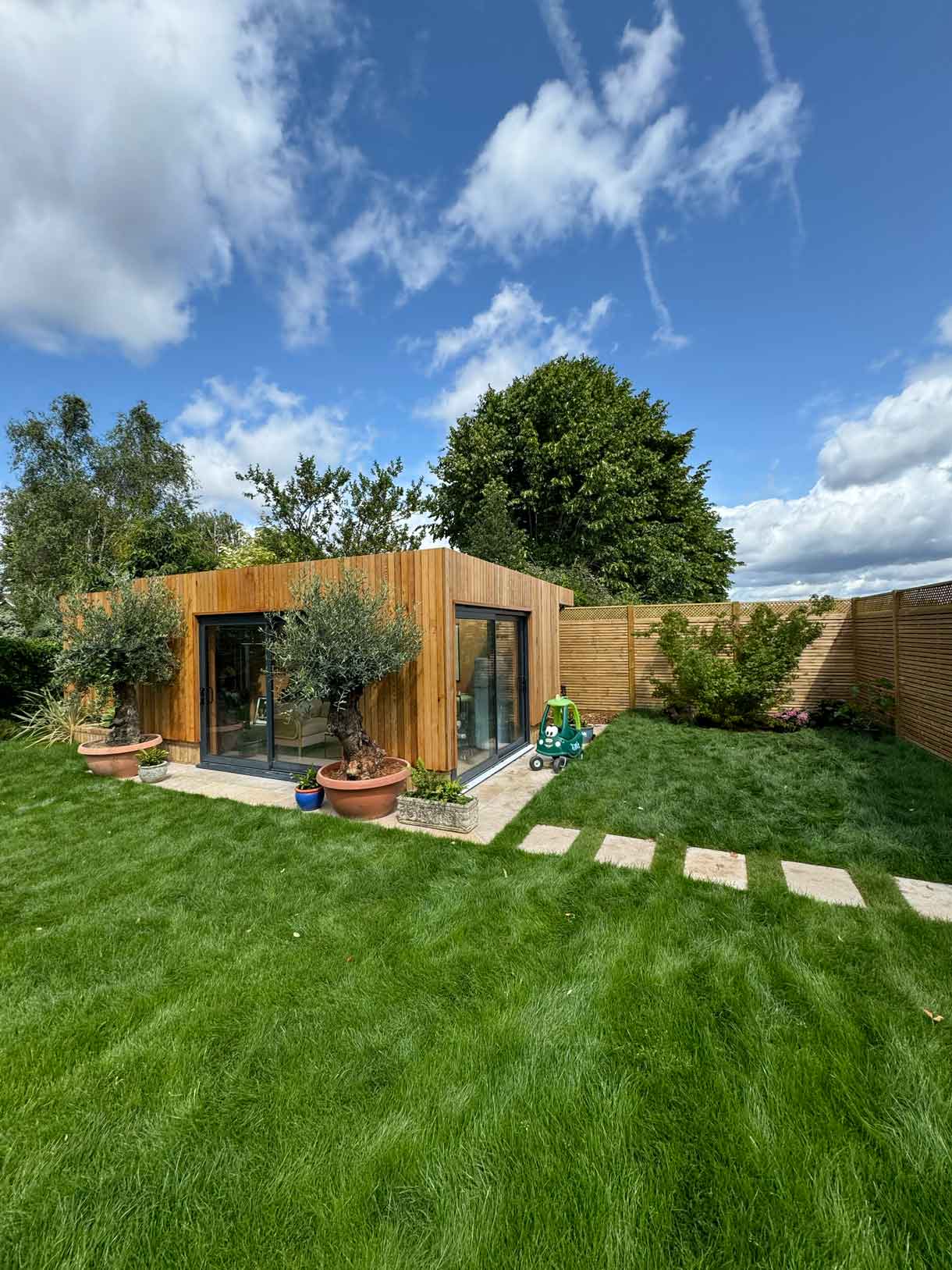 Contemporary wooden garden room with stepping stone path across lawn.