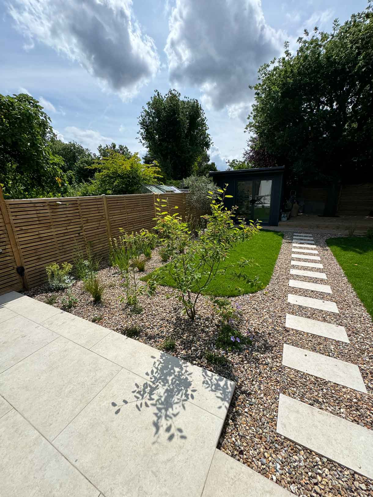 Stepping stone path running across lawn to garden room at the rear.