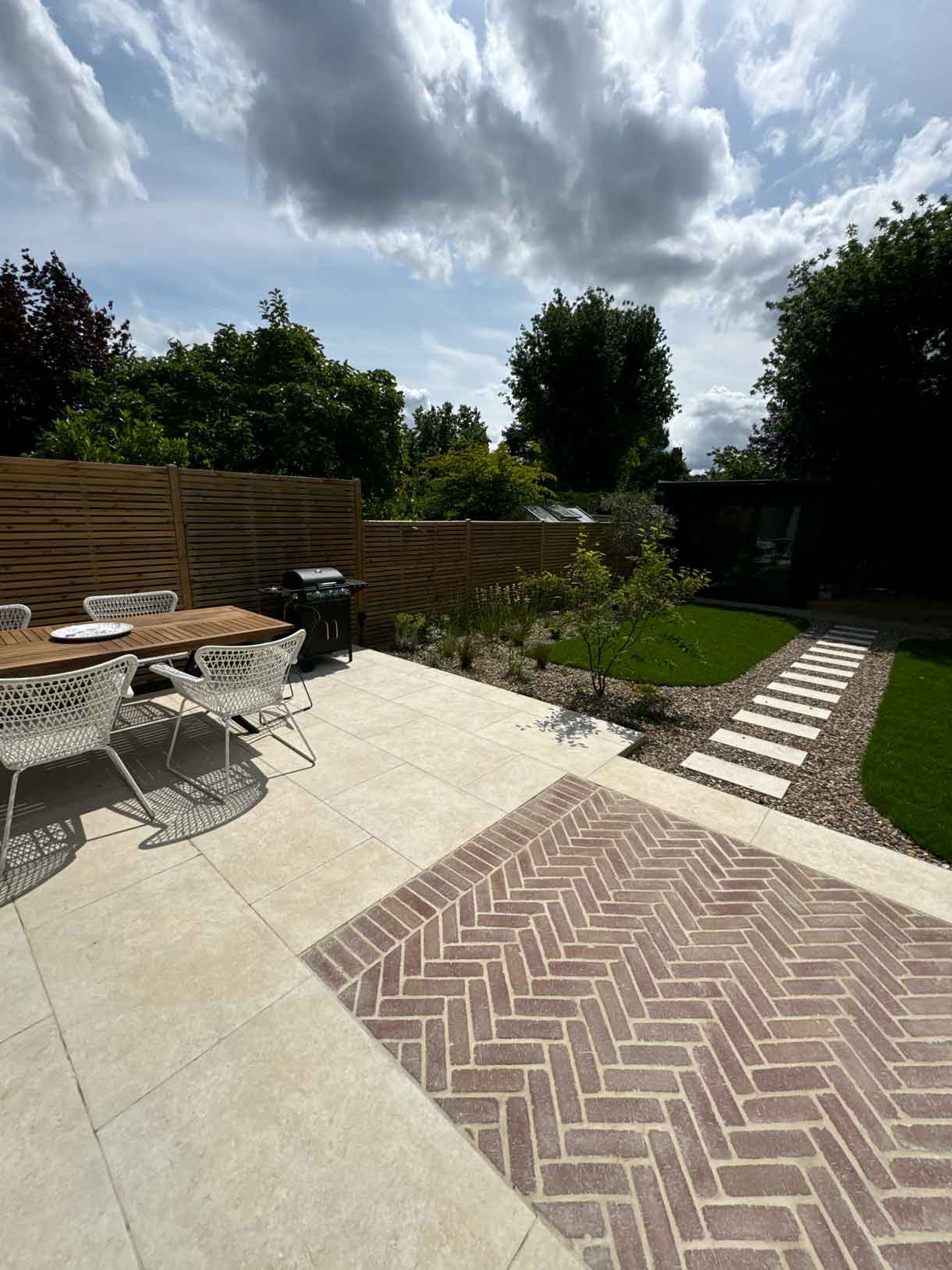 Patio with outdoor seating beside lawn and planting borders.