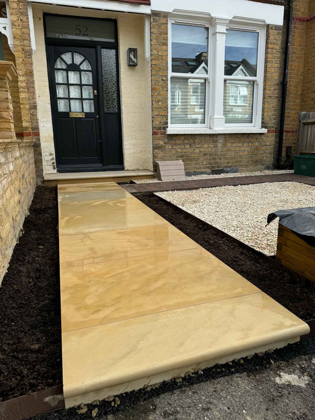 Close-up of a new sandstone step with vent detail beneath the front door.