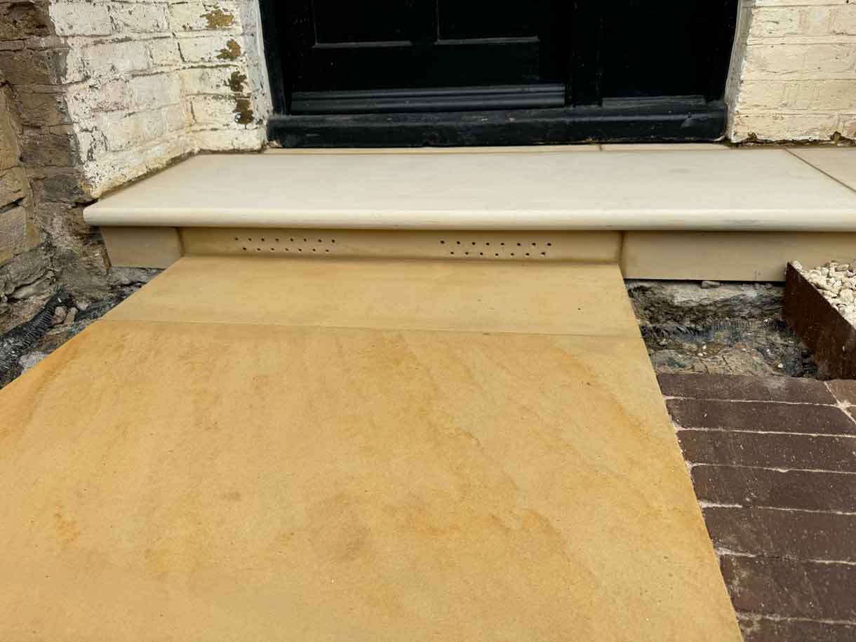Sandstone step and paved threshold outside the front entrance.