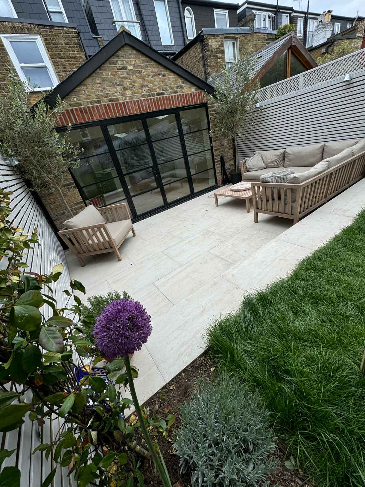 Patio seating area with timber slatted fencing and large glazed doors.