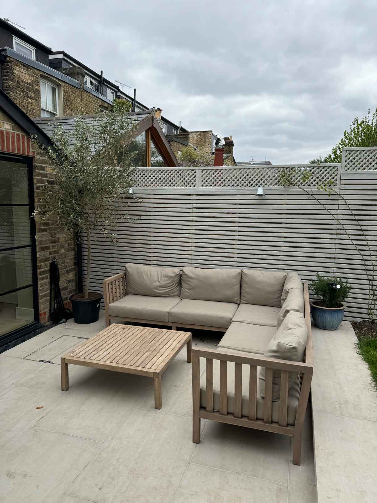 Outdoor sofa set placed against a slatted garden fence in the rear patio.