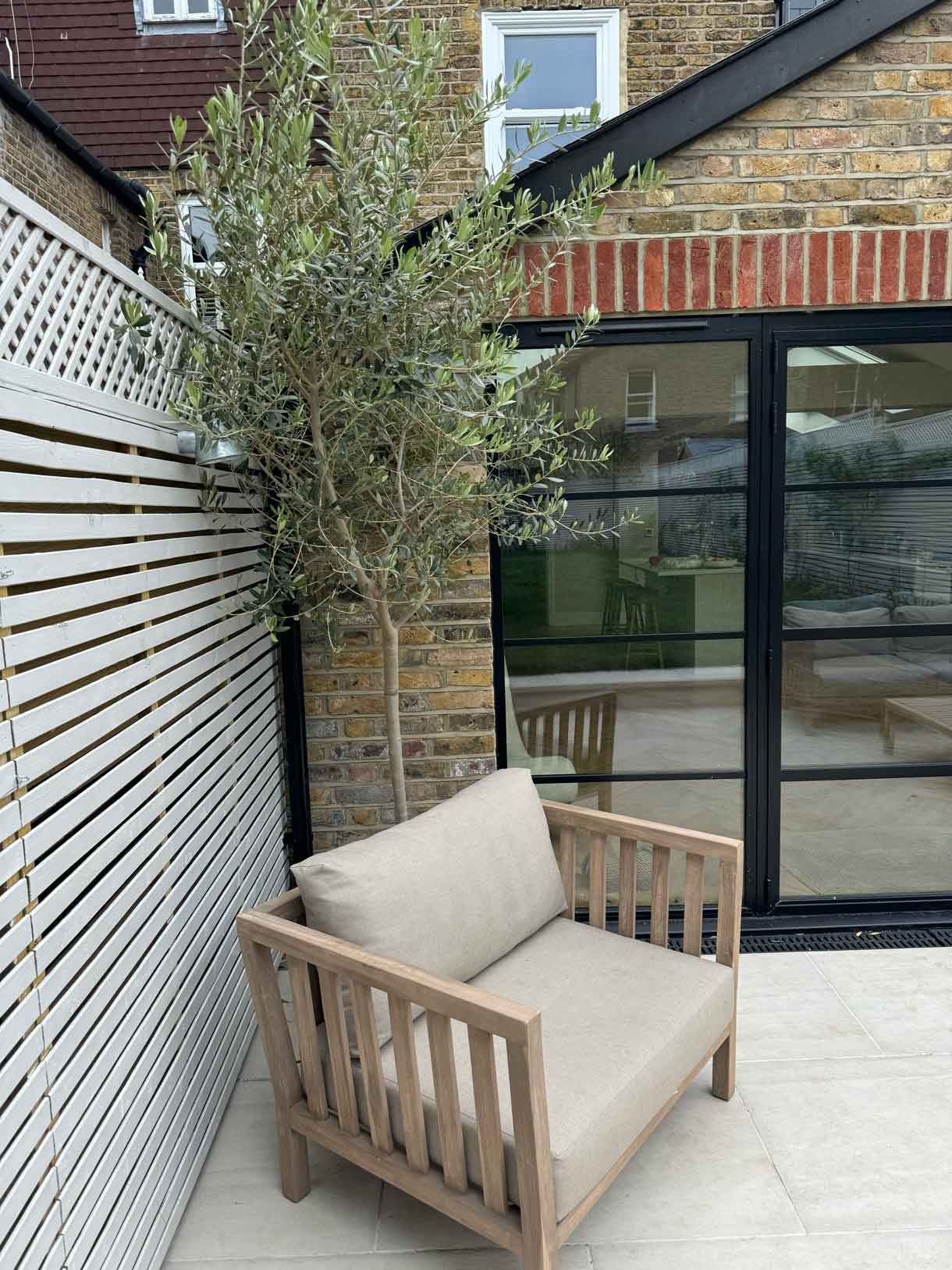 Patio seating area with timber slatted fencing and large glazed doors.