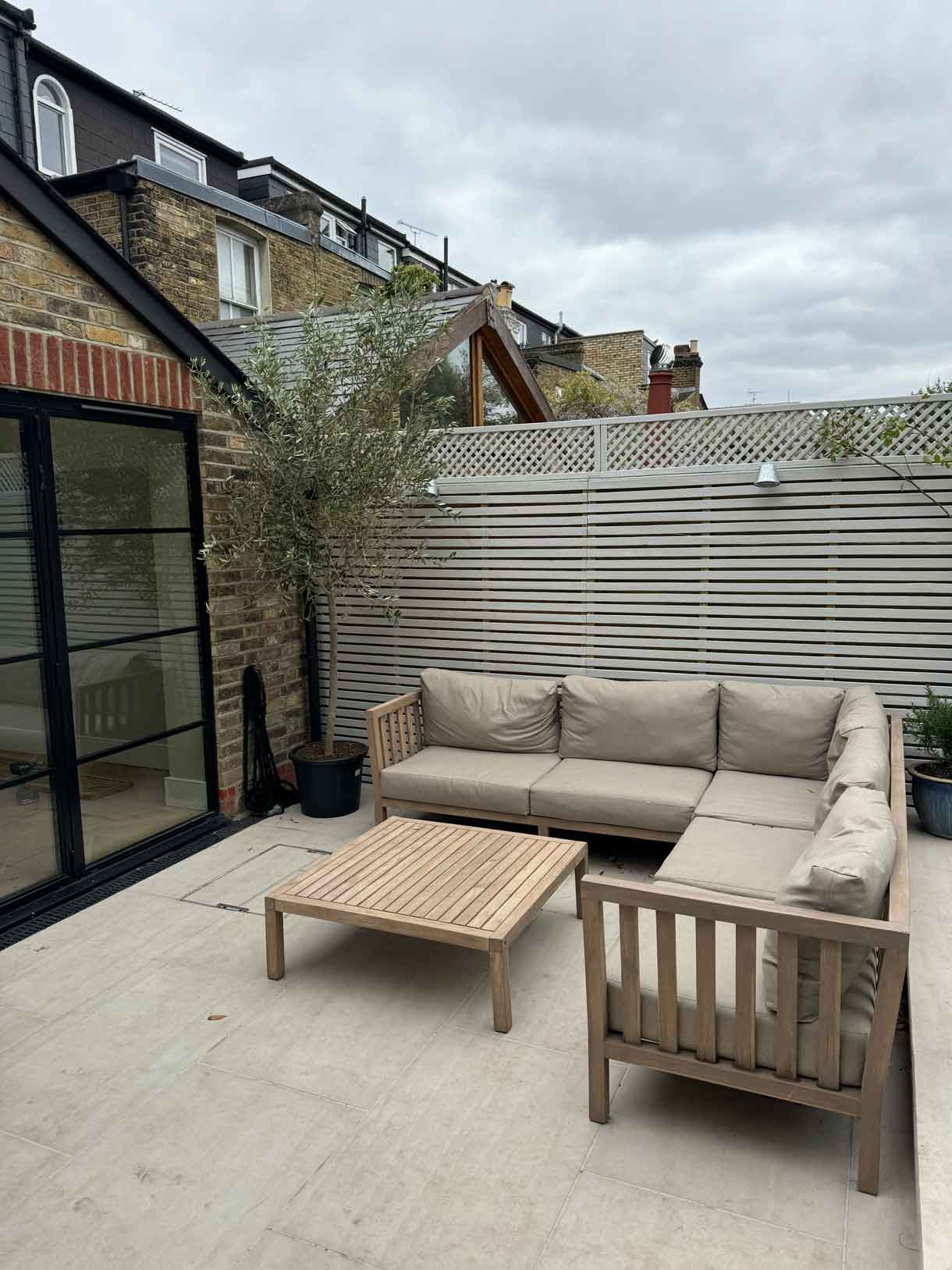 Outdoor L-shaped sofa and coffee table on light stone paving.