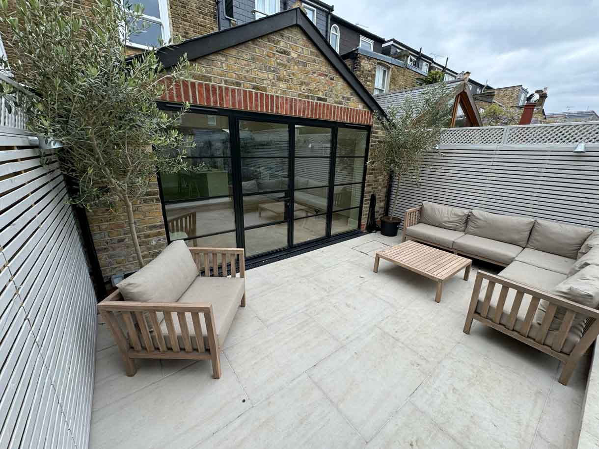 Garden seating arranged around a low timber coffee table on stone paving.