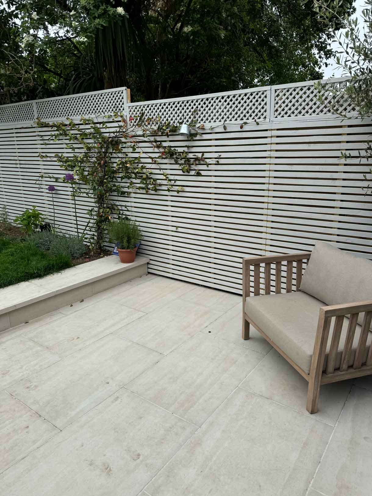 Corner of patio with white slatted fencing and low planter.