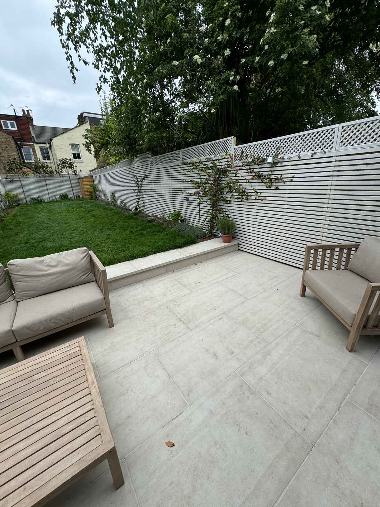 Paved patio with two timber chairs facing a newly planted border.
