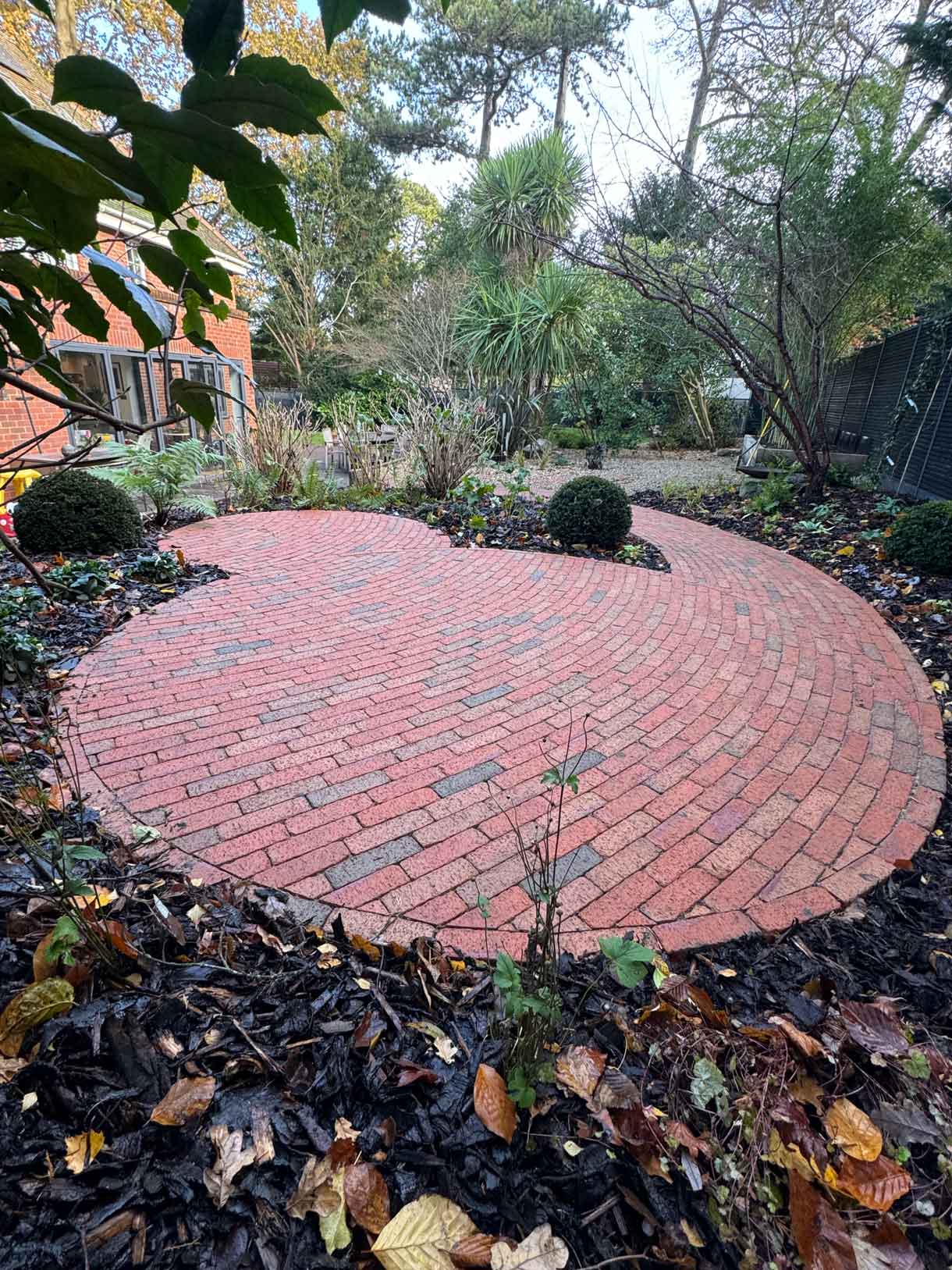 Circular timber seating platform under a tree with surrounding woodland planting.