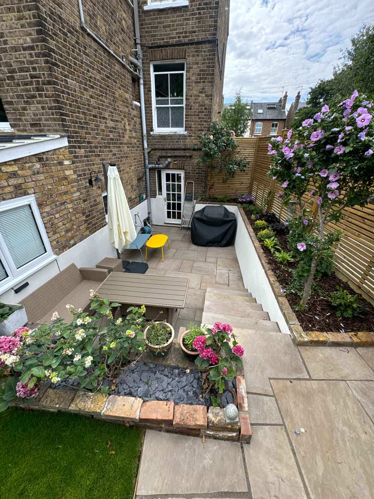 Freshly planted garden border with gravel mulch and young shrubs leading towards the garden office.
